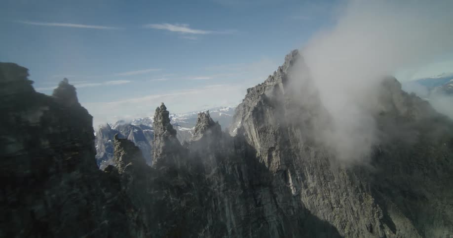 An extremely tall mountain range with pointy peaks above a valley