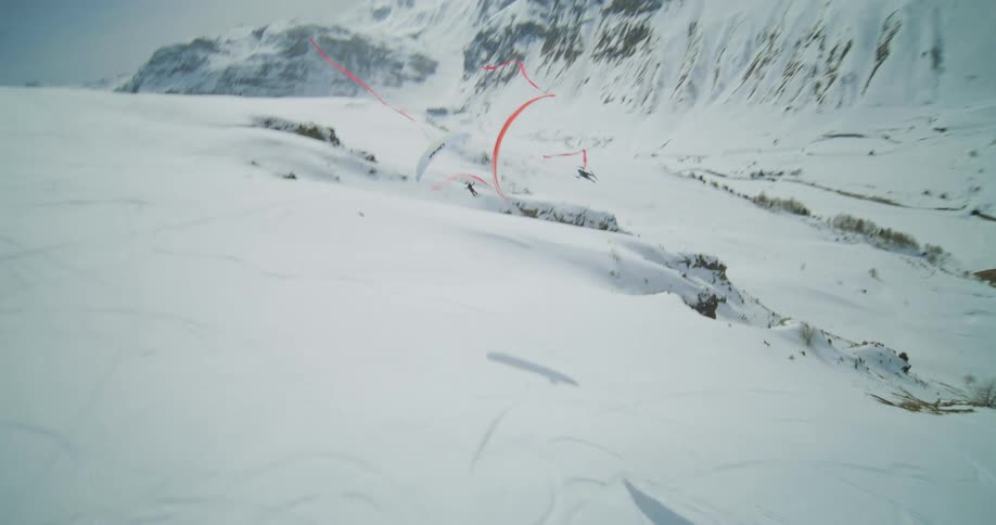 People para gliding over a snowy mountain range