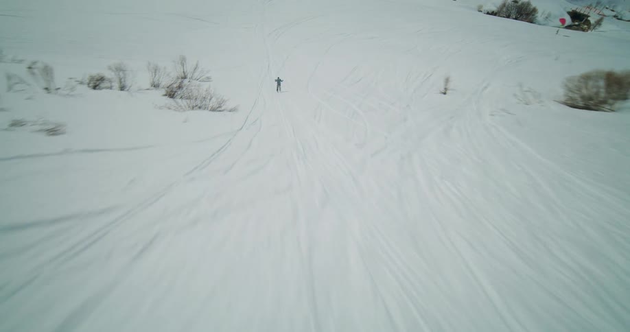 A skier skis down a mountain slope at high speed during the day