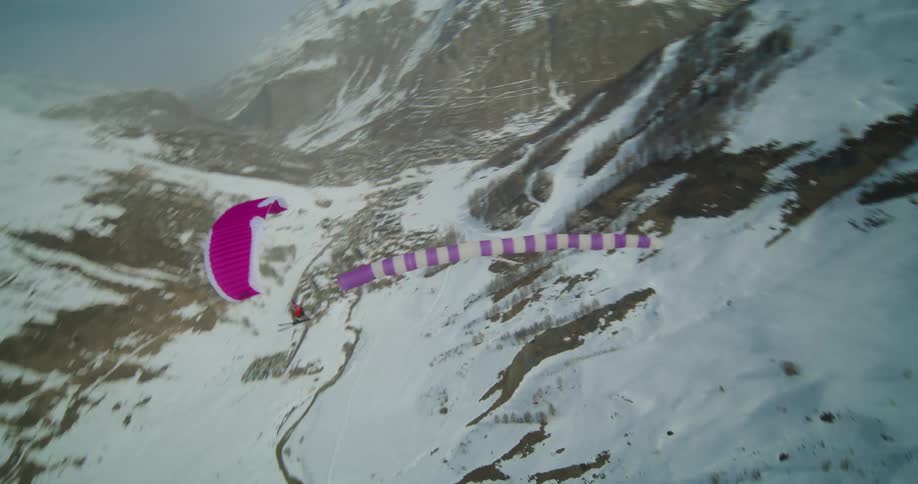 Ski glider glides over snowy mountain range on sunny day