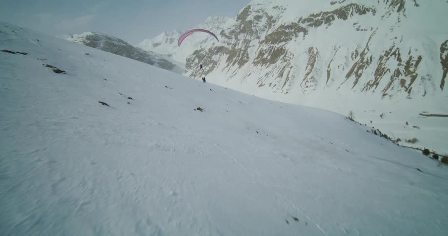 People parasailing over a snow covered mountain range