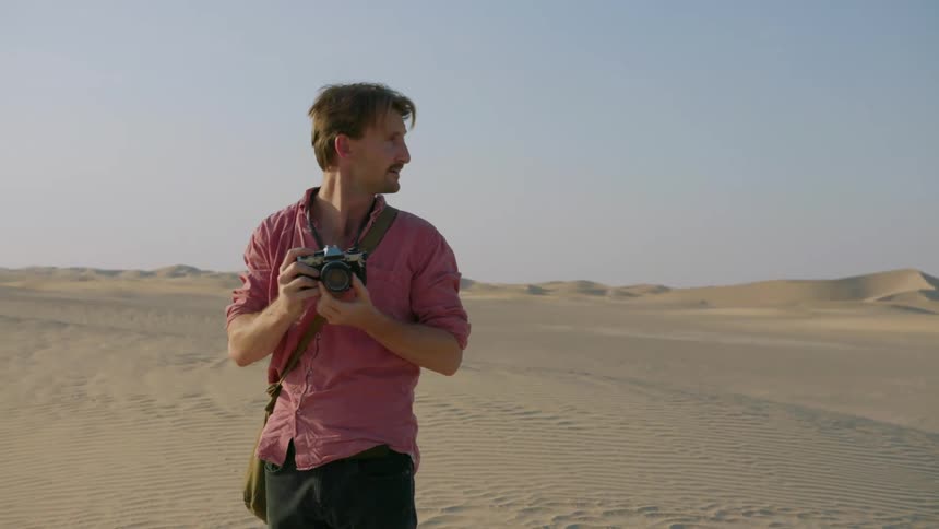 A photographer takes a picture in a desert