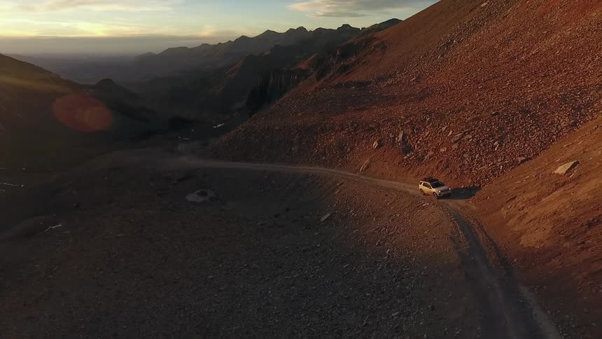 A car drives along a dirt path in a canyon