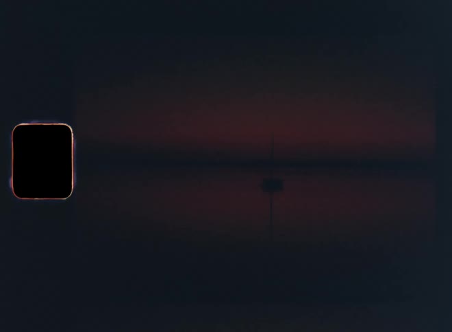 Panning 8 mm vintage footage of a dark lake and the black silhouette of a sailing boat in twilight with red sky