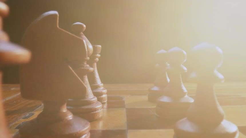 A light shines down on a chess game with chess pieces