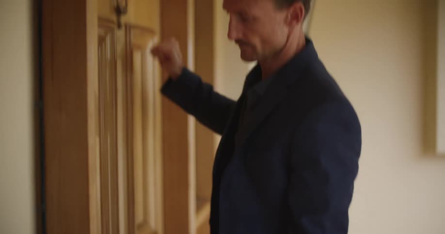 Man holding an eviction notice folder in his left hand knocking on a massive wooden front door of a house