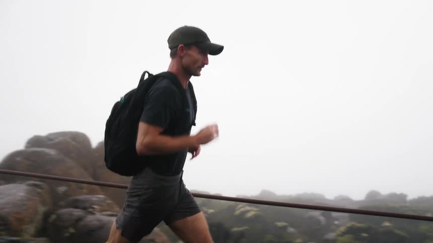A man runs along a roped off trail in a canyon