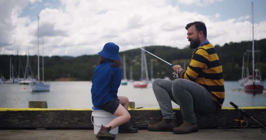 A man and his daughter fish along a pier