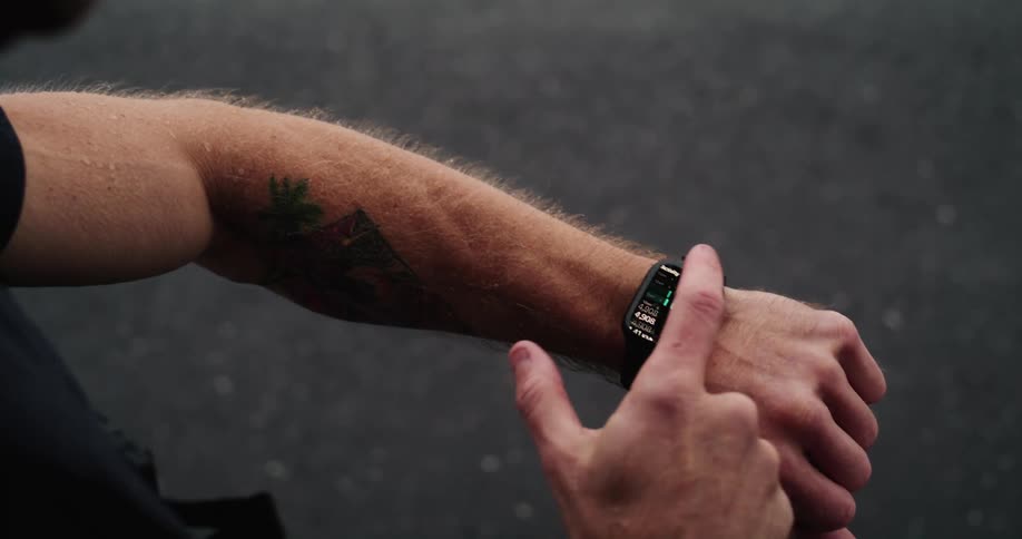 A man is outdoors and looking at his watch in the day time