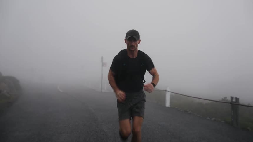 A man exercising runs down a foggy road
