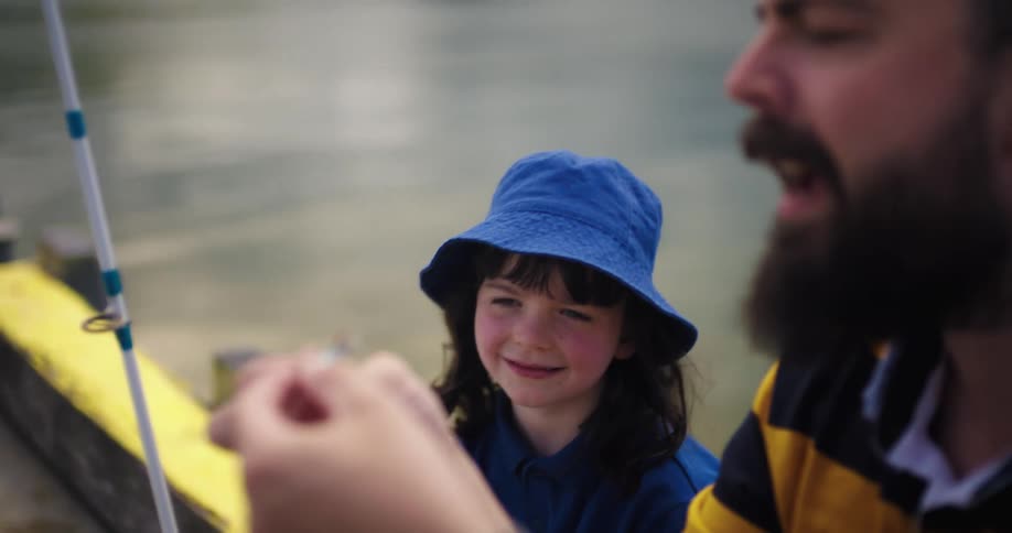 Father and daughter are fishing around the day time on a lake