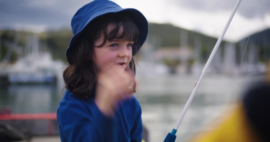 A child is talking while holding a fishing pole