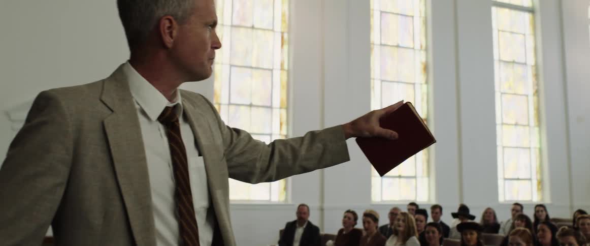 Preacher in church holds bible and walks about while presenting sermon to congregation