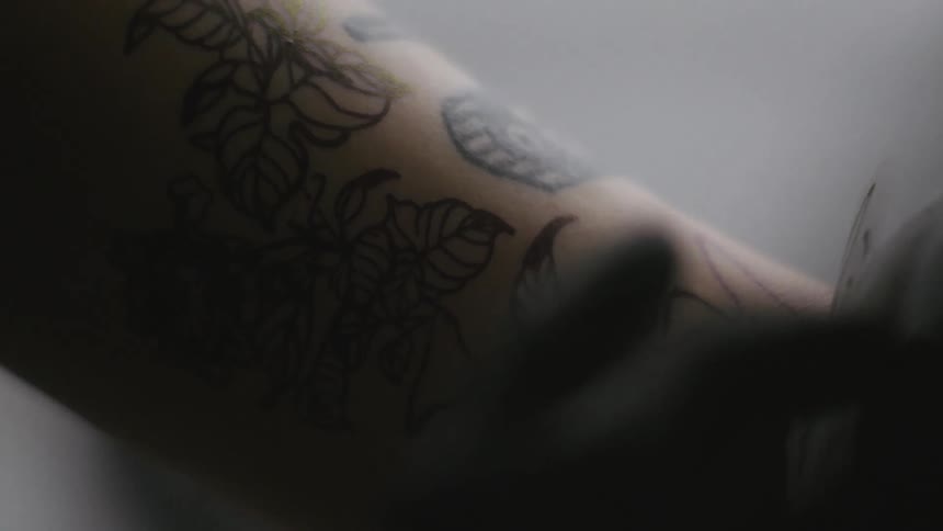 A tattoo artist is transferring a picture on to someones arm and they are carefully lifting the paper with the image