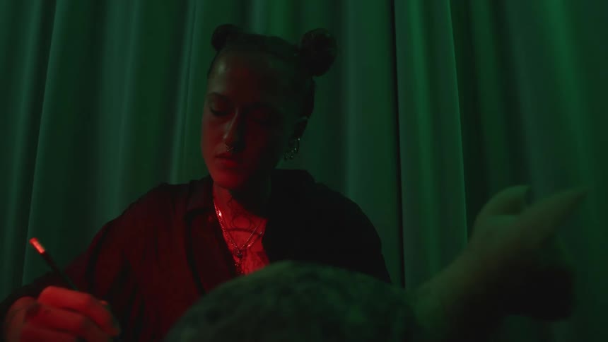 A woman writing in a dark space looking intently