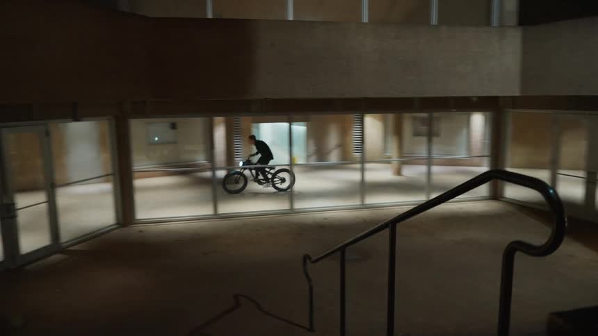 A man is riding a bike through a building at night