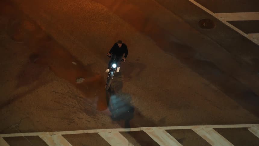 A man is riding a motorcycle through an empty street