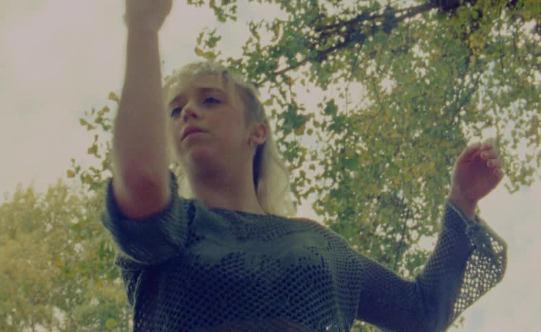 A woman is dancing outdoors during sunset