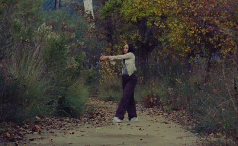 A woman is dancing in a wooded area by herself