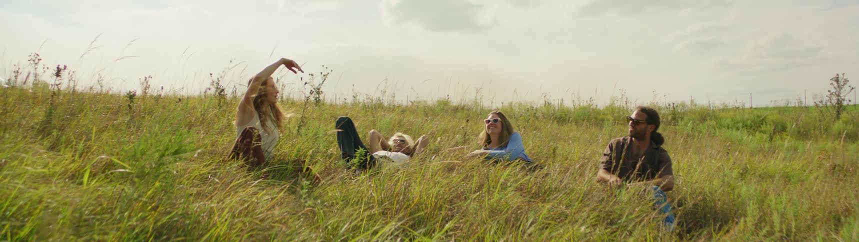A group of friends are sitting in a field of grass together