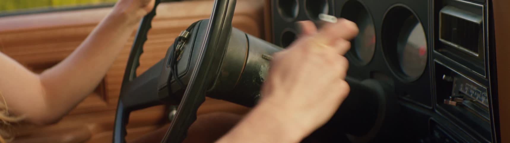 A young woman is starting her car in the middle of the day time