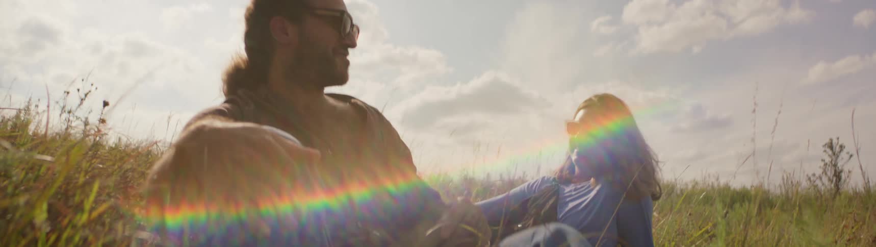 Man and woman are sitting outdoors in a grass field
