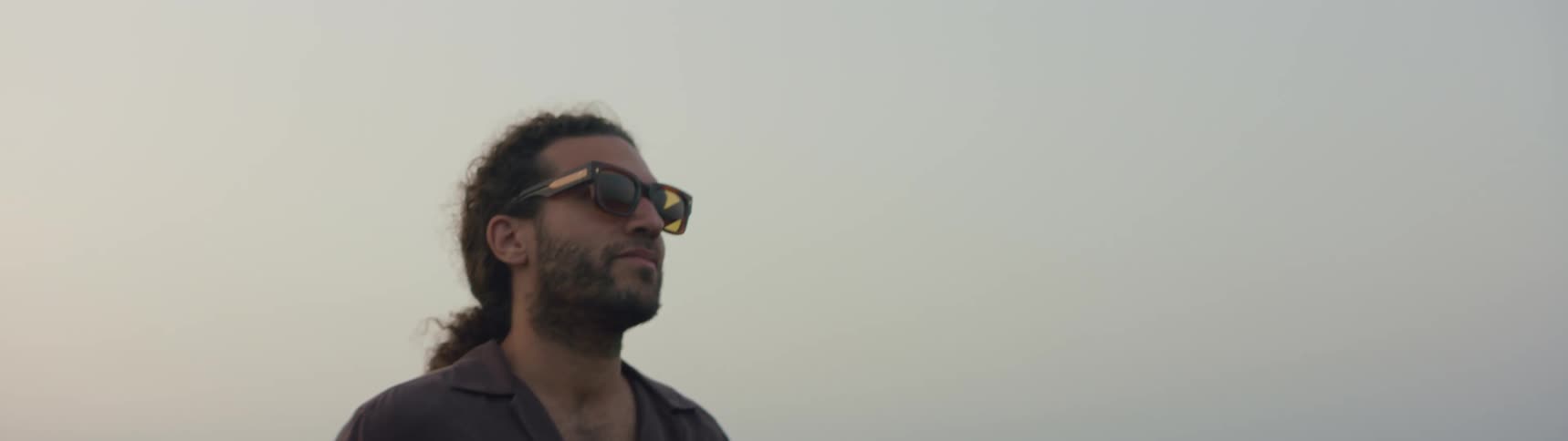 A man is standing outdoors while wearing sunglasses