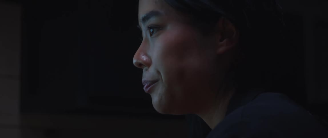 Light from a computer monitor reflects off a woman's face as she focuses on what is in front of her