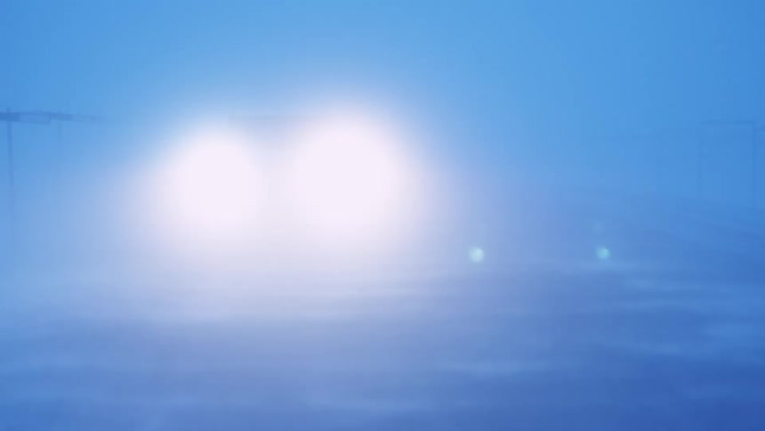 Vehicle with bright headlights passes truck moving the opposite direction during obscuring weather