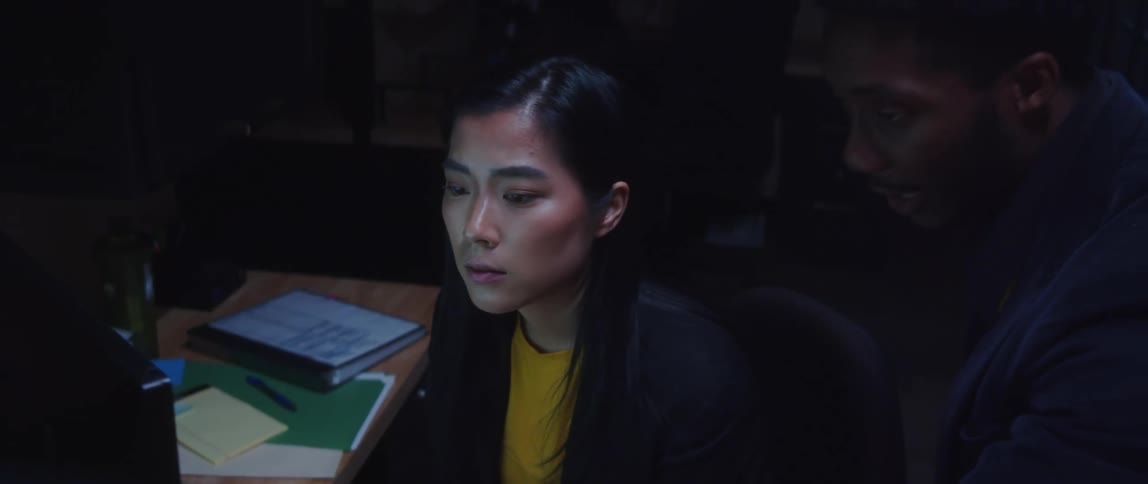 Two coworkers discuss contents on computer display near desk