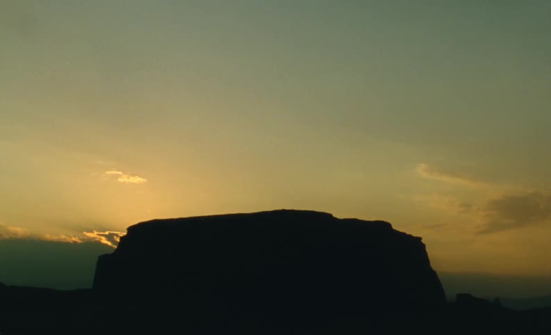 The sun setting behind a cliff