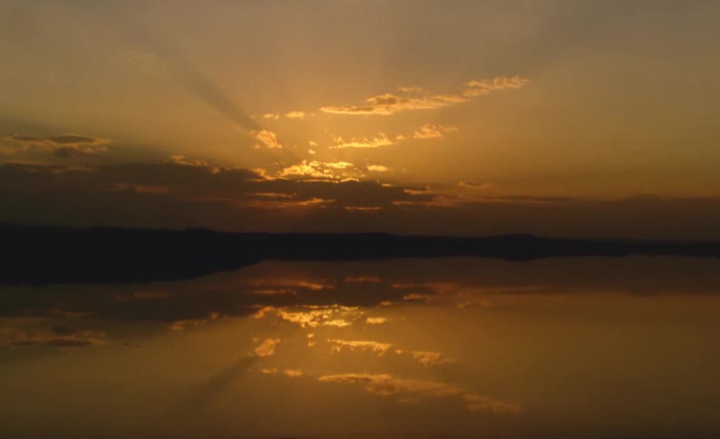 Sun setting behind clouds reflecting off water