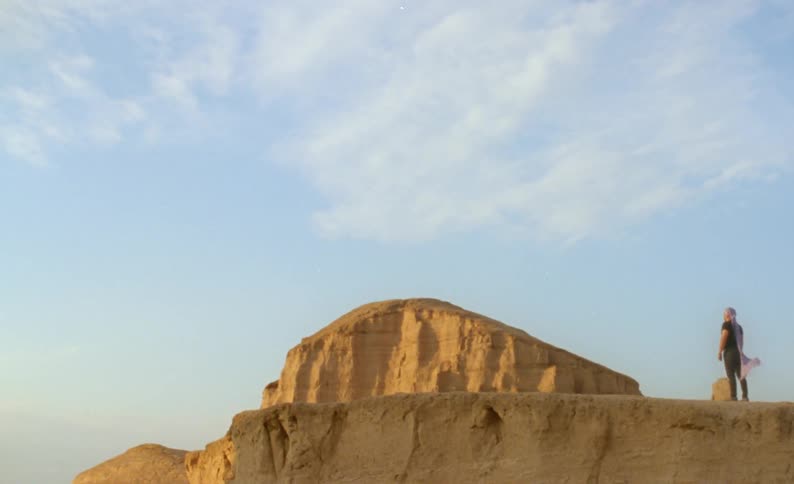 A man is standing outdoors in a mountainous area