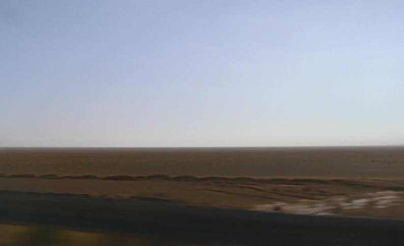 Driving fast through barren plains at sunset