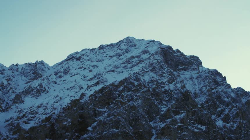 Snow covers a mountain ridge under a clear sky