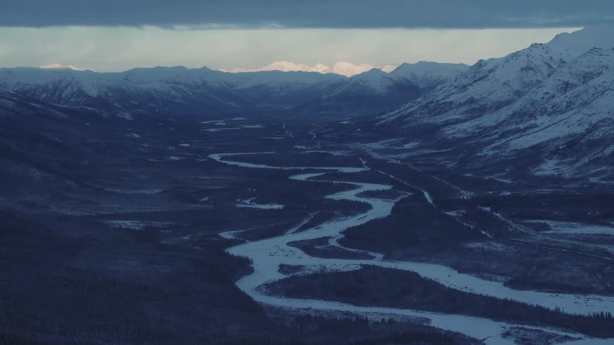 Panoramic view of a river valley and some snow covered mountains