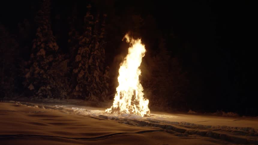 A chair burns in a bonfire in a snowy field