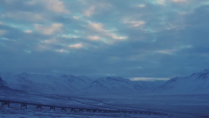 A snowy covered landscape and mountains in the distance with a track along the whole landscape