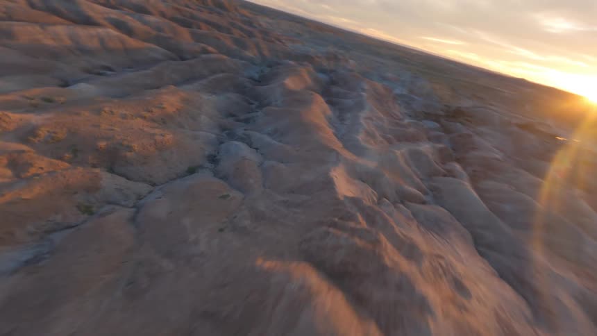Portions of badlands remain in shadow as sun sits on the horizon