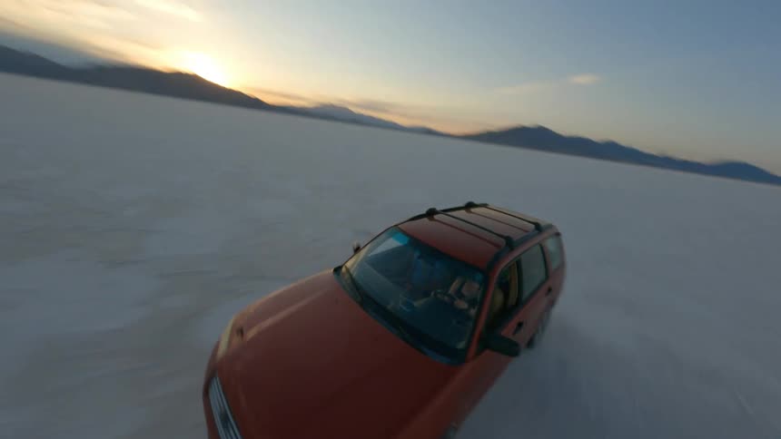 A person is driving a car through a desert area at dusk
