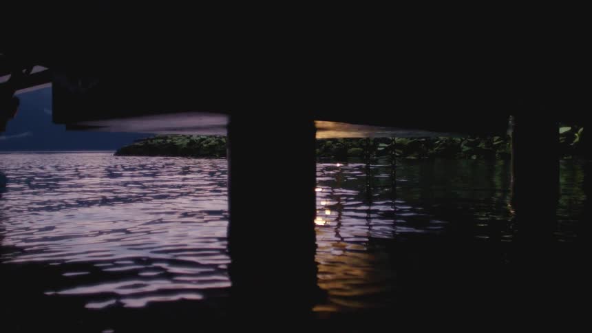 Water reflecting light underneath a building on piers