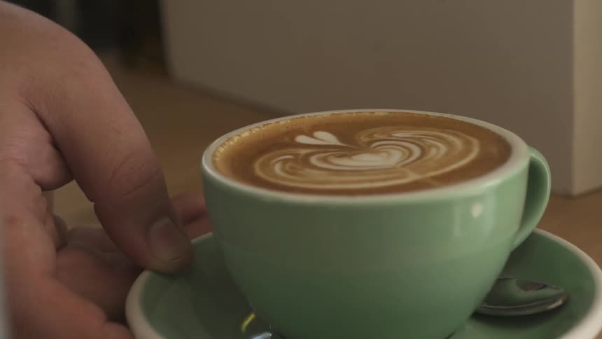 A person pushes forward a cup of coffee