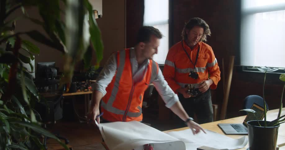Two men in an office look at blueprints together
