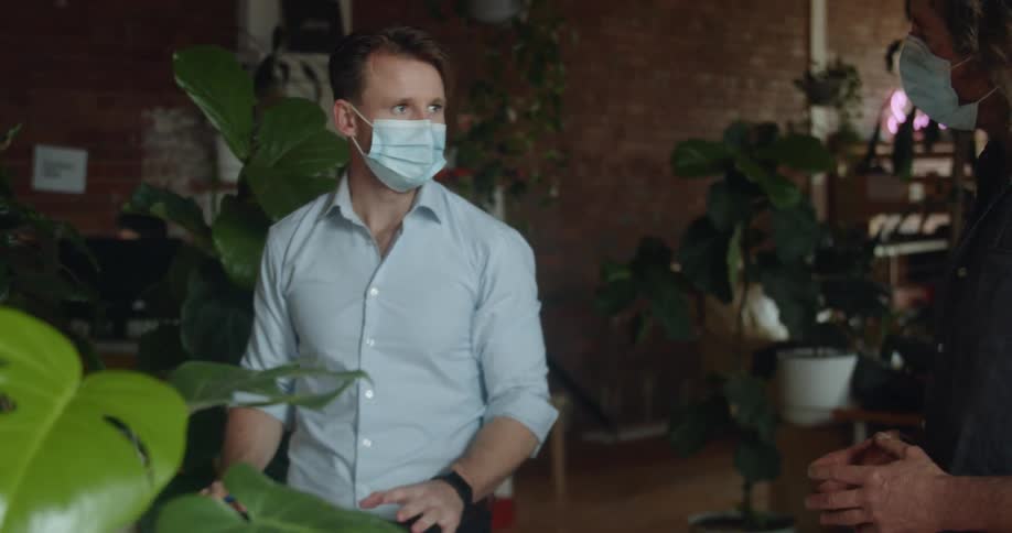 Coworkers wearing face masks having conversation inside office or store