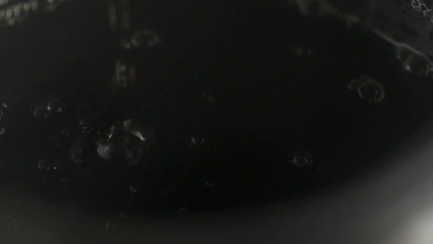 A dark fluid dripping into a container