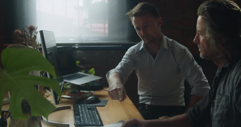 Two people going over a design on a computer and blueprints