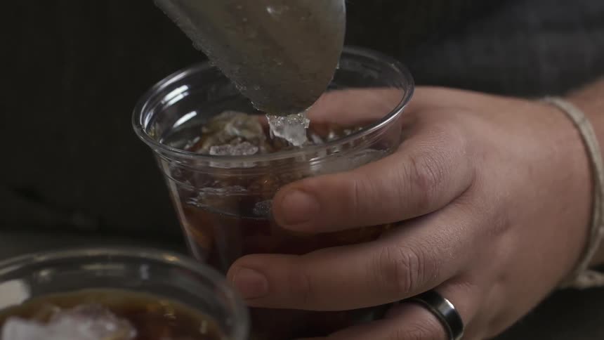A man scoops ice cubes into a drink