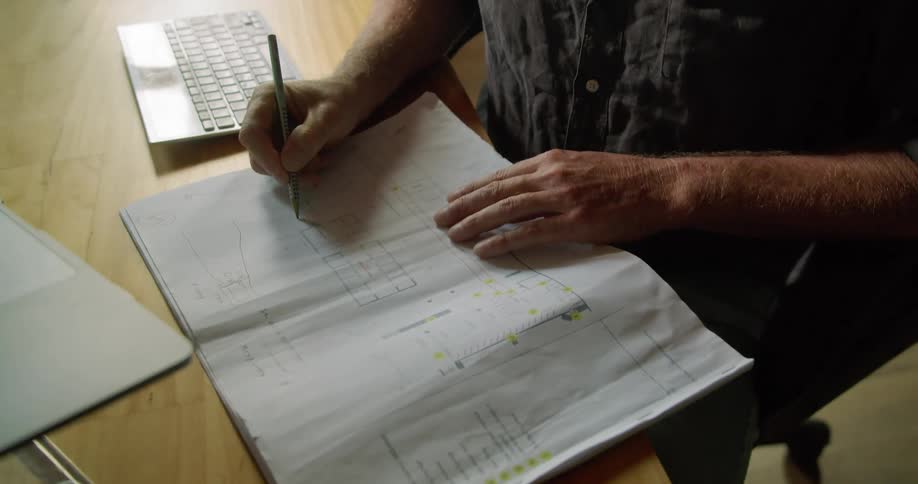A man writes on a piece of paper while sitting at a desk