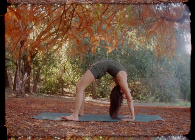 Young woman stretches over a mat outdoors caught on vintage film