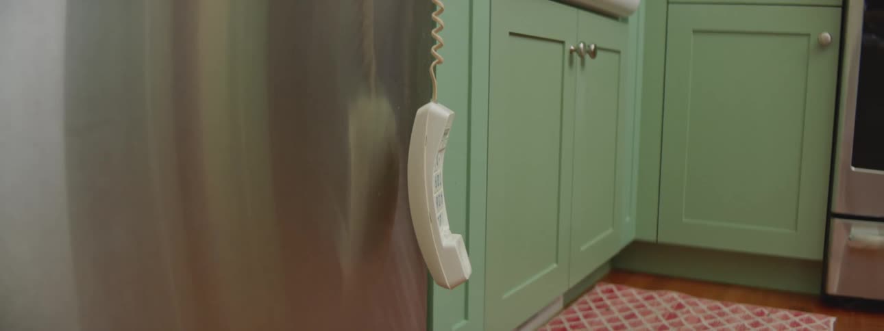 A landline telephone hangs from its cord in the kitchen